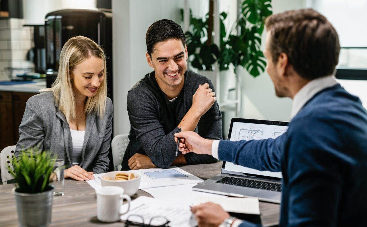 Young happy couple going through housing plans with real estate agent.